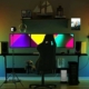 ein Arbeitstisch mit mehreren Bildschirmen, zwei Tuya Smart-Lampen an jedem Ende in den Ecken