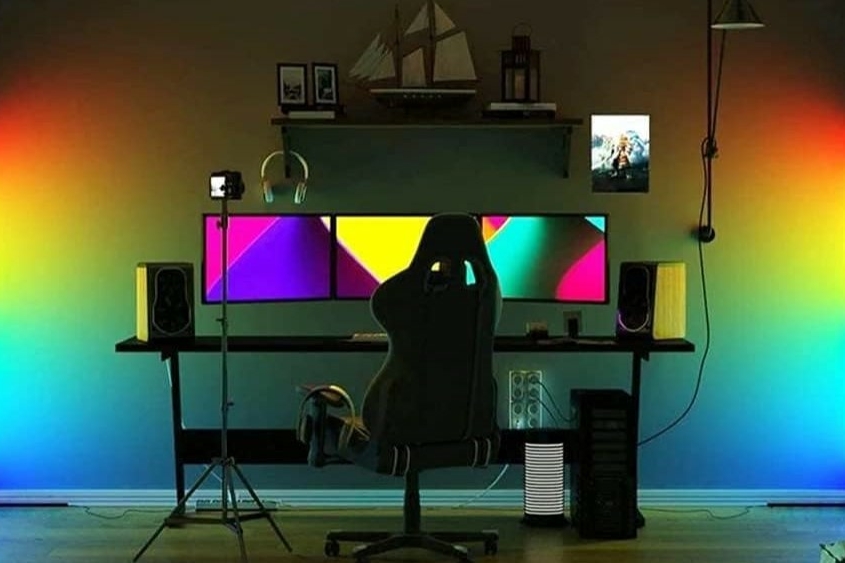 ein Arbeitstisch mit mehreren Bildschirmen, zwei Tuya Smart-Lampen an jedem Ende in den Ecken