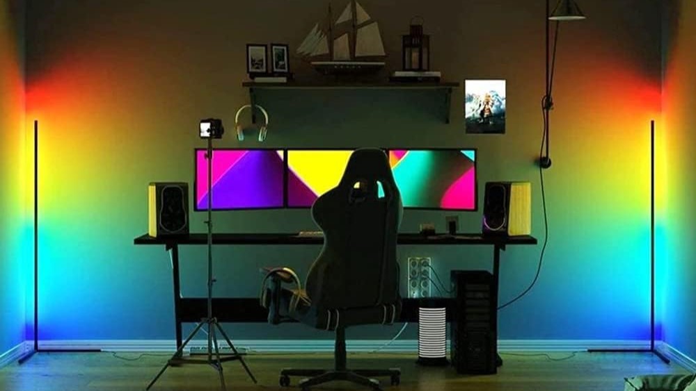 un tavolo da lavoro con schermi multipli, due lampade intelligenti Tuya su ogni estremità negli angoli